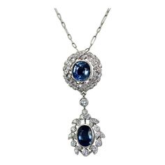 This is part of Chairish’s Fine Jewelry assortment.  Vintage Sapphire Diamond 18K Drop Necklace  This necklace is made in 18K White Gold and features 2 beautiful Blue Sapphires. The style is modern yet bears a vintage drop necklace style. The necklace is 18" long and has (1) oval Sapphire of 1.25 carats the other Sapphire drop is round and weighs .75 carats. This totals 2 carats of Sapphires. Diamond surround the Sapphires in wreath style and the bottom Sapphire has a Diamond surround. The Diamo Oval Diamond Necklace With Jewels, Exquisite Oval Jewel Necklaces, Oval White Gold Necklace With Jewels, Luxury Oval Jeweled Necklaces, Luxury Jeweled Oval Necklaces, Elegant Oval Drop Necklace For Formal Occasions, Oval Diamond Necklace With Detachable Pendant, Elegant Oval Drop Necklace For Anniversary, Oval Jeweled Necklaces For Anniversary