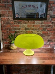 a large yellow vase sitting on top of a wooden table next to a brick wall