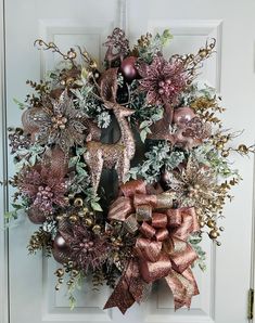 a christmas wreath on the front door decorated with ornaments and deer's head hanging from it