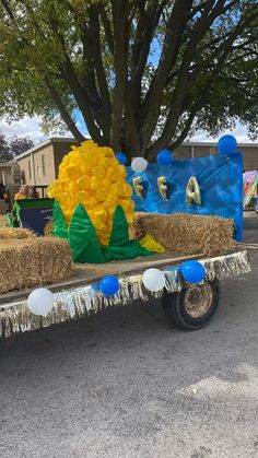 a truck with hay bales and balloons on the back is parked in front of a tree