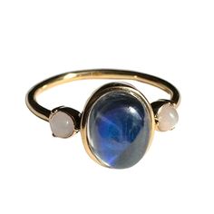 a gold ring with a blue stone and two white stones on the front, set against a white background