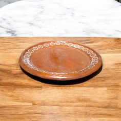 a brown bowl sitting on top of a wooden table next to a white marble counter