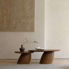 two wooden tables with vases on them in front of a white wall and floor