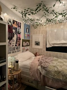 an unmade bed in a small room with lights strung from the ceiling above it