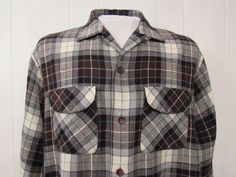 "Vintage 1960s button down shirt. Made of black, gray, brown and white plaid Rayon/wool. Has two chest flap pockets, button front, top button loop and button cuffs. Made by Acrallama. Size large. Actual measurements are: 48\" around the chest 48\" at the waist 18\" shoulder seam to shoulder seam 24.5\" shoulder seam to end of cuff 29\" overall length In very good condition." Classic Brown Flannel Shirt With Buttons, Brown Collared Flannel Shirt With Buttons, Vintage Fall Shirt With Placket, Vintage Brown Flannel Shirt With Button Closure, Brown Vintage Flannel Shirt With Button Closure, Vintage Collared Flannel Shirt With Button Closure, Vintage Plaid Shirt With Pockets, Retro Collared Flannel Shirt With Button Closure, Retro Collared Flannel Shirt With Pockets