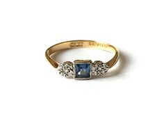 a three stone ring with diamonds on the sides and a blue sapphire in the middle