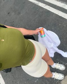 a woman in green shirt and white skirt holding an orange can