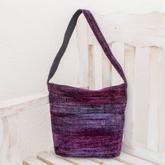 a purple bag sitting on top of a wooden bench next to a white wall,