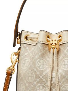 This Tory Burch mini bucket bag perfectly captures Instagram-worthy style with its monogram pattern, coordinating hardware, and roomy yet compact size. Ideal for on-the-go adventure snapping, its top handle and removable shoulder strap provide versatile carrying, while the drawstring closure keeps valuables secured. Crafted from a durable cotton blend, it withstands everyday use while flaunting the signature charms of a top designer brand. Everyday Bucket Bag In Monogram Canvas With Gold-tone Hardware, Everyday Monogram Canvas Bucket Bag With Gold-tone Hardware, Travel Bag With Brass Hardware And Monogram Canvas, Monogram Canvas Bucket Shoulder Bag With Adjustable Strap, Monogram Canvas Bucket Bag With Gold-tone Hardware, Travel Bucket Bag With Branded Hardware, Monogram Canvas Crossbody Bucket Bag With Removable Pouch, Tan Monogram Canvas Shoulder Bag With Gold-tone Hardware, Designer Gold Bucket Bag For Travel