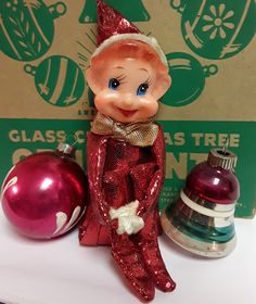 an elf figurine sitting next to christmas ornaments