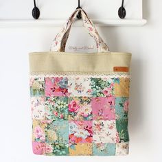 a multicolored patchwork tote bag hanging from a hook on a wall