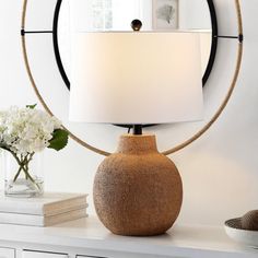 a table with a lamp on it and a vase next to it in front of a mirror