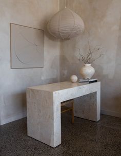 two white vases sitting on top of a table next to a wall mounted art piece