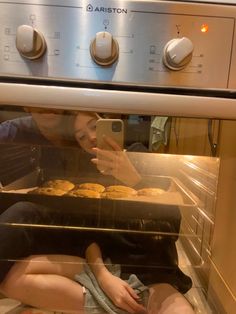 a woman taking a photo of cookies in an oven