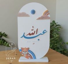 an arabic greeting card with a teddy bear and rainbows in the sky, on top of a wooden table