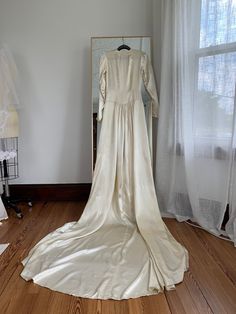 "Exquisitely preserved authentic 1930's wedding gown. Made of a medium weight soft ivory satin, classic long sleeves with pointed cuffs and six covered buttons, sweetheart neckline, pleated bust, full skirt with chapel train. Side zipper closure. Measurements- Bust- 34\" Waist- 27\" Hips- 36\" Length- 56\" Sleeve length-24\" *Condition* Excellent vintage condition. Zipper may need to be replaced as it's pretty difficult to make go up and down. Minor discoloration from age. Freshly cleaned and re Long Sleeve Cream Wedding Gown, Cream Long Sleeve Gown With Fitted Bodice, Cream Gown With Fitted Bodice And Long Sleeves, Full Length Bias Cut Gown For Wedding, Vintage Wedding Gown With Bias Cut, Vintage Cream Satin Gown, Silk Long Sleeve Wedding Gown, Long Sleeve Silk Wedding Gown, Vintage Long Sleeve Formal Gown