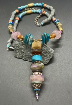 "Bohemian Longer gem necklace with a wired and beaded Pendant.  I just love colors, shapes, and different sizes in materials.  You will see apatite stone, lavender amethyst, vintage glass, wood, brass, copper, wood, lamp work beads hand crafted from Thailand and glass tube beads from Africa, in this unique necklace.  I wired the pendant and stacked up the beads.  I crafted the curved portion of this necklace and beaded onto wire; this helps to hold the curved shape.  Then I beaded strands from t Beaded Bohemian Czech Glass Crystal Necklace, Bohemian Beaded Czech Glass Crystal Necklaces, Bohemian Beaded Czech Glass Crystal Necklace, Bohemian Czech Glass Beaded Necklace With Wire Wrap, Bohemian Wire Wrapped Beaded Necklaces With Czech Glass, Bohemian Wire Wrapped Czech Glass Beaded Necklace, Bohemian Czech Glass Wire Wrapped Beaded Necklace, Bohemian Long Beaded Necklaces With Stones, Bohemian Long Beaded Stone Necklace