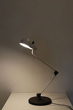 a desk lamp sitting on top of a white table next to a black light bulb