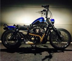 a blue and black motorcycle parked in front of a white wall with a shadow on the ground