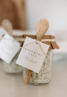 two small glass jars with wooden spoons in them and tags attached to the lids