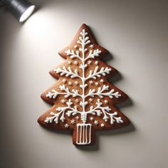 a decorated christmas tree shaped cookie on a white wall next to a black light fixture