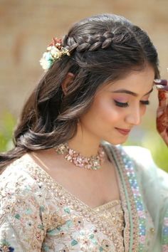 a woman wearing a bridal outfit and holding her hands to her face while looking down