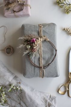 two wrapped presents with flowers and twine tied to them, sitting on a table