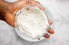 a hand holding a glass jar filled with white powder