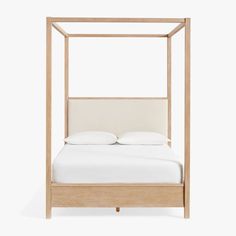 a white bed with a wooden frame and pillows on it's headboard, in front of a white background