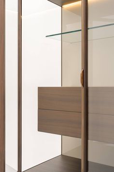 an open closet with glass shelves and wooden doors