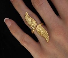 Gold Angel Wing Ring: ▪️  This gorgeous statement piece will make the perfect gift for yourself or a loved one. The ring is adjustable and will fit different finger sizes   ▪️  Made of gold plated brass   ▪️  The model in the picture is a size 7     Care Instructions:   ▪️  Gold plating can last for years if looked after correctly   ▪️  Keep away from water, sweat, chemicals, perfumes, lotions, etc. If it begins to tarnish in areas of high friction, the color will appear a darker orange   ▪️  How to clean: dip a cotton ball in a solution of mild dish soap and water. Rub gently and then rinse, dry, and buff     We hope you enjoy! We have family ties with jewelers in Istanbul, Turkey who hand make our pieces with love. Your happiness is our utmost priority, and we accept returns if it doesn' Wings Ring, Wing Ring, Angel Wing Ring, Angel Ring, Metal Wings, Gold Angel Wings, Ring Elegant, Gold Angel, Gold Rings Fashion