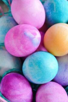 a basket filled with dyed easter eggs on top of a table