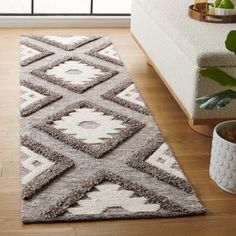 a large rug with an abstract design on the floor next to a plant in a living room