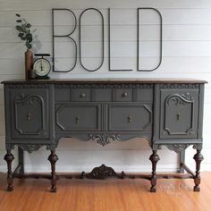 an old dresser is painted gray and has ornate carvings on the top, along with a clock