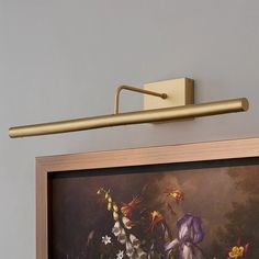 a painting is hanging on the wall next to a light fixture with a long arm