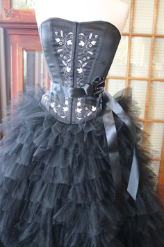 a black corset with a large bow on it's belt is sitting on a mannequin