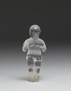 a clear glass figurine is standing on a gray surface