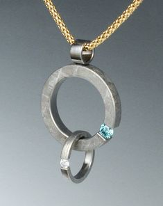 This simple pendant is made of two solid rings of Gibeon meteorite that have been tension set with a .19 carat irradiated blue Diamond to represent the earth and a .07 carat white diamond to represent the moon. The small ring holding the white diamond floats freely around the larger ring with the blue diamond.  The meteorite has been etched with nitric acid to reveal the characteristic patterns, or Widmanstatten figures, of iron meteorites, and an etched meteorite ring acts as the bale.  The pen Modern Oval Pendant Jewelry For Anniversary, Hand Forged Modern Jewelry For Anniversary, Modern Hand Forged Jewelry For Anniversary, Sterling Silver Pendant Jewelry With Tension Setting, Fine Jewelry Pendant With Tension Setting, Unique Sterling Silver Jewelry With Tension Setting, Modern Diamond Pendant Jewelry, Unique Jewelry With Tension Setting For Gift, Unique Jewelry With Tension Setting As Gift