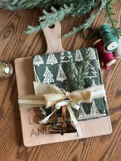 a christmas present wrapped in green and white fabric next to a tree with twine spools