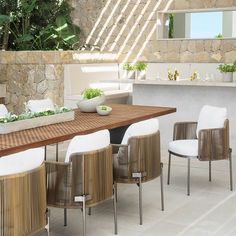 an outdoor dining table with white chairs and a bowl of fruit on the counter top