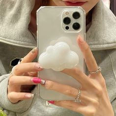 a woman taking a selfie with her cell phone in front of her face and holding a cloud