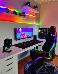 a desk with a computer and gaming chair in front of it, all lit up by colorful lights