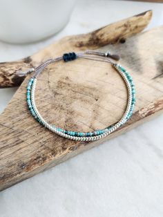 This delicately-strung exclusively crafted bracelet has two strands of tiny Japanese Miyuki glass beads in galvanized Silver and blue sea mix on natural grey silk cord. All beads have  a uniform shape with a sparkly finish, perfect for a minimalist look that can be dressed up or down. Finished with a macramé sliding clasp in waxed cotton to adjust to your size. Wear this alone or layer and stack with other bracelets. A great holiday essential that goes with everything. Treat yourself or spoil so Turquoise Beaded Bracelet As A Gift, Bohemian Silver Friendship Bracelets With Tiny Beads, Silver Friendship Bracelets With Tiny Round Beads, Multi-strand Beaded Bracelet With Tiny Beads As Gift, Multi-strand Beaded Bracelet As A Gift, Multi-strand Tiny Beads Bracelet As Gift, Minimalist Green Beaded Bracelets With Tiny Beads, Minimalist Green Beaded Bracelet With Tiny Beads, Turquoise Multi-strand Bracelets With Tiny Beads