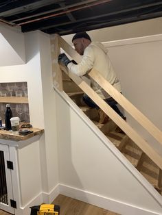 a man is working on the bottom of a ladder in a room with wood flooring