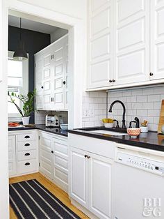 a kitchen with white cabinets and black counter tops, along with a rug on the floor