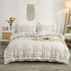 a white bed sitting in a bedroom next to a table with flowers on top of it