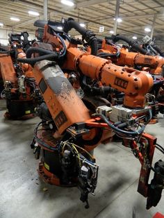 an orange robot sitting in a warehouse next to other robots