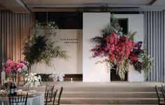 a stage set up for a wedding with flowers and greenery on the side wall