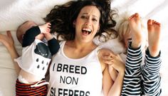 a woman laying on top of a bed next to two babys wearing matching pajamas