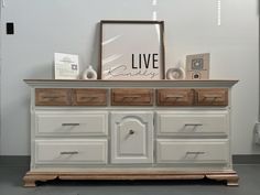 a white dresser with drawers and pictures on top